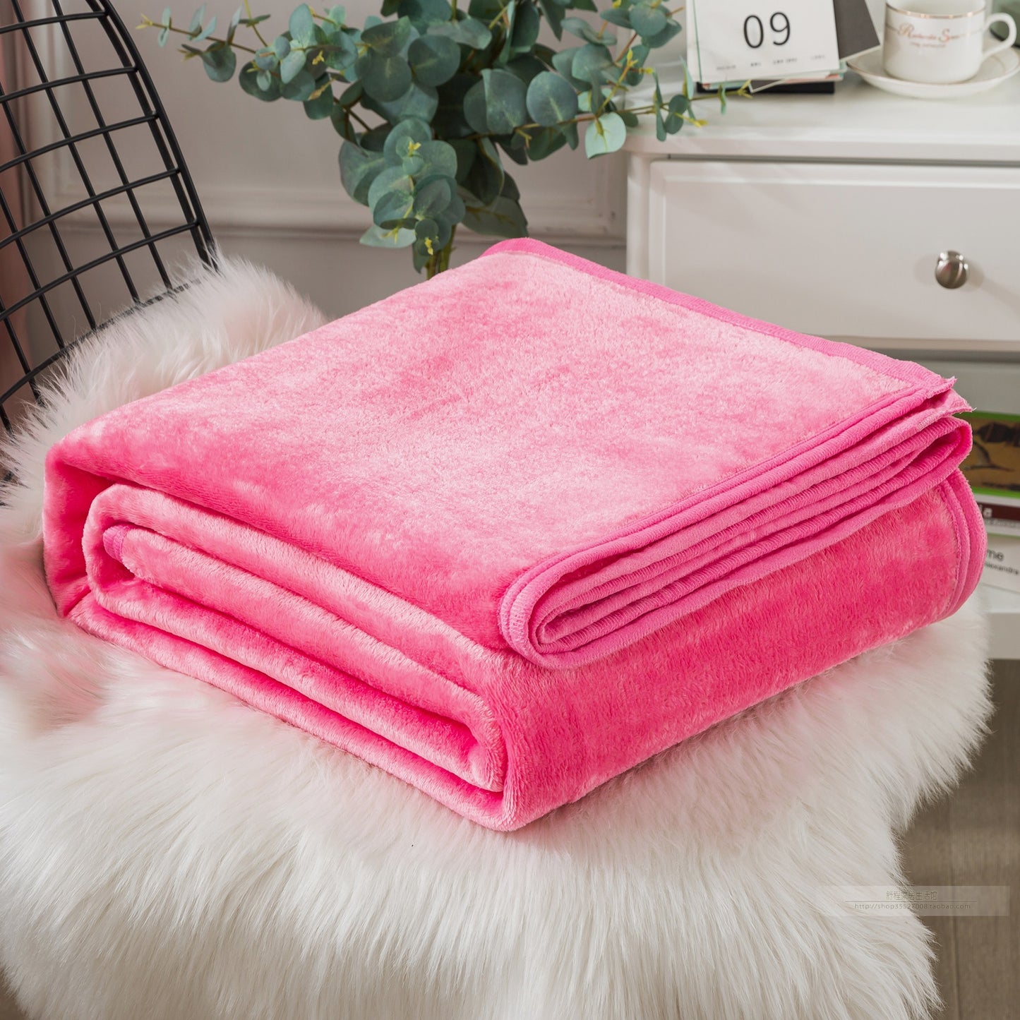 Folded pink blanket on a white fur surface with decorative elements.