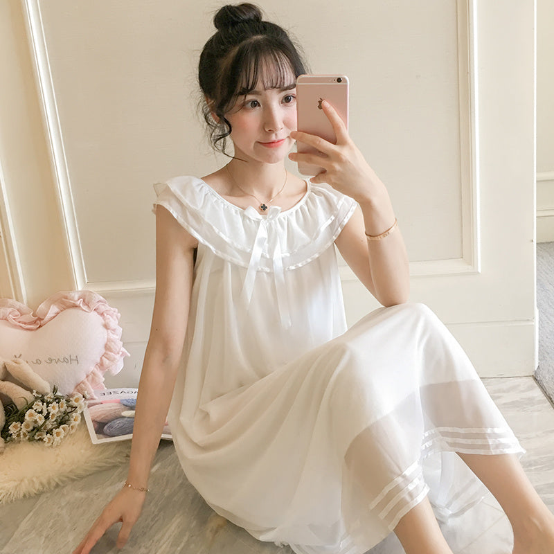 Woman in a white dress taking a selfie in a softly lit room.