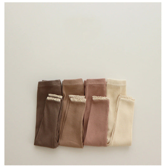Folded ribbed garments in brown and beige on a light gray background