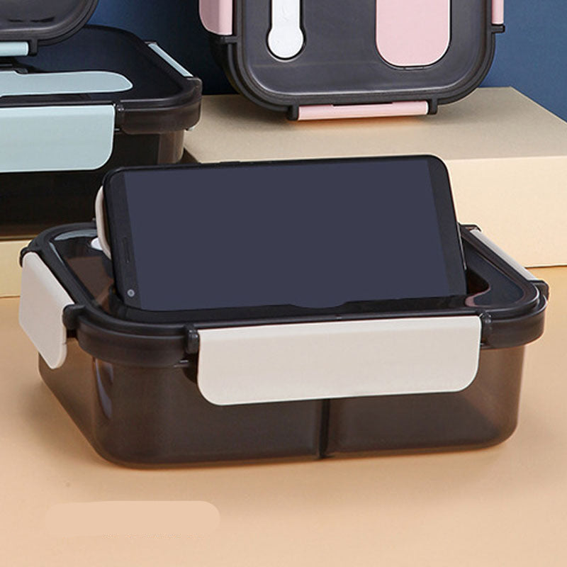 Assorted colors and styles of plastic lunch boxes with compartments, accompanied by a plastic fork and spoon, displayed with food inside.