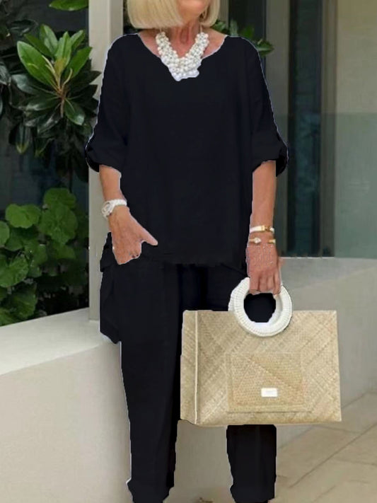 Woman in black outfit holding a beige handbag with a white handle.