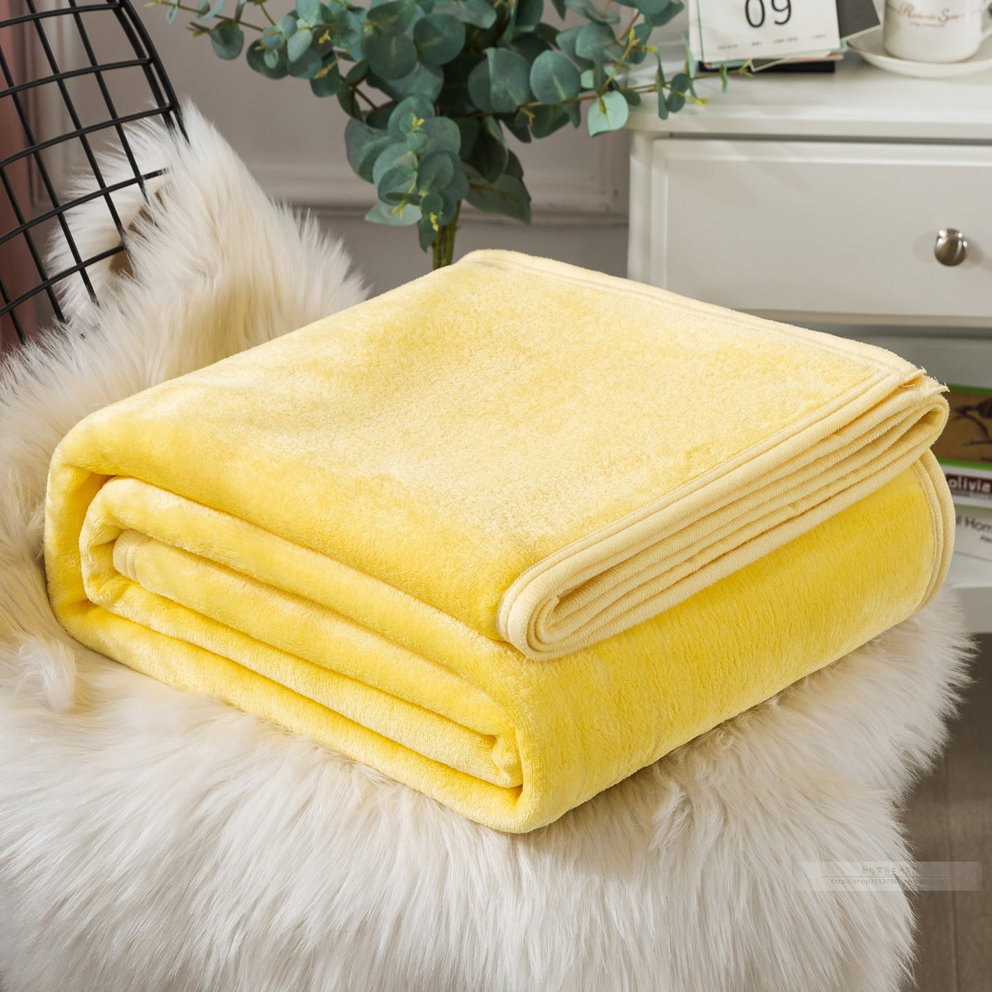 Yellow blanket folded on a fluffy white surface.