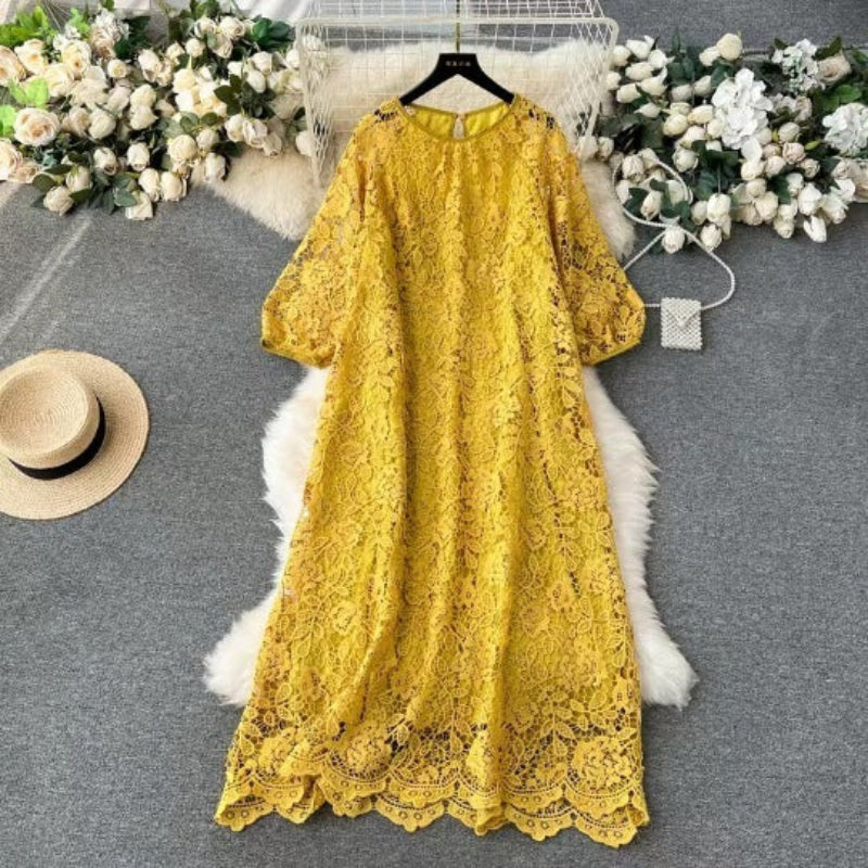 Yellow lace dress on a hanger with flowers and a hat in the background