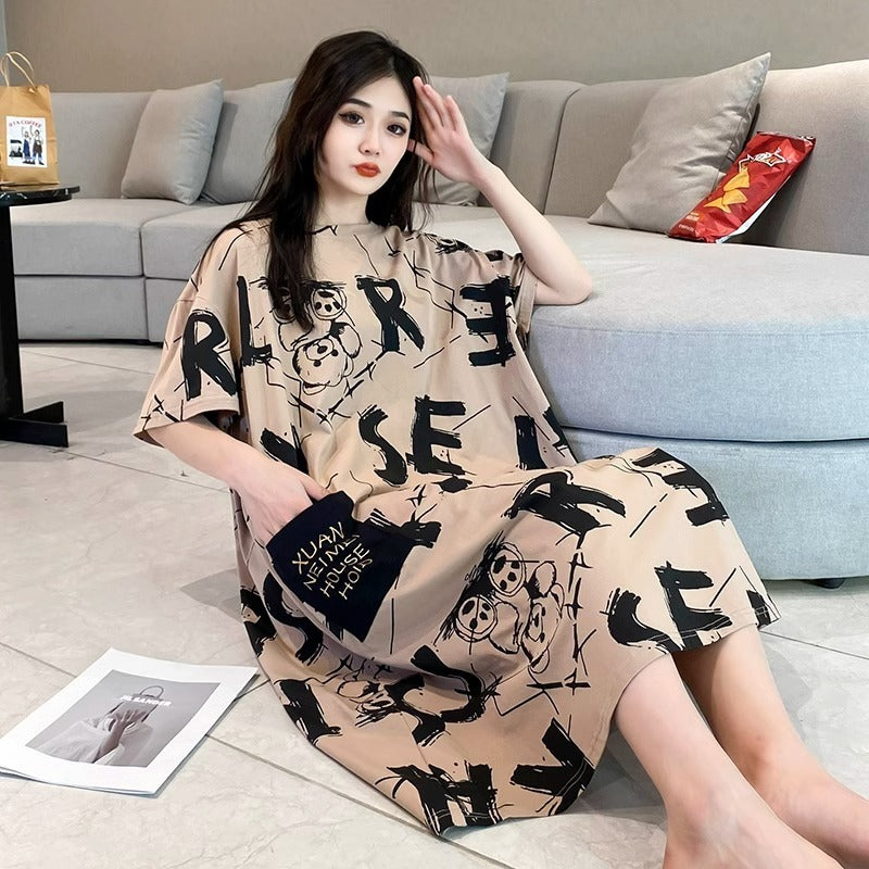 Woman wearing a beige dress with black text and graphics in a living room setting.