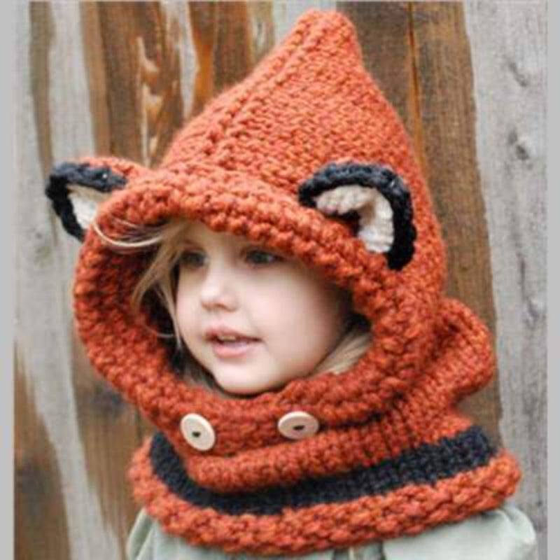 A baby wearing a beige knitted hat with a hood that has a bear face design and wooden button details.