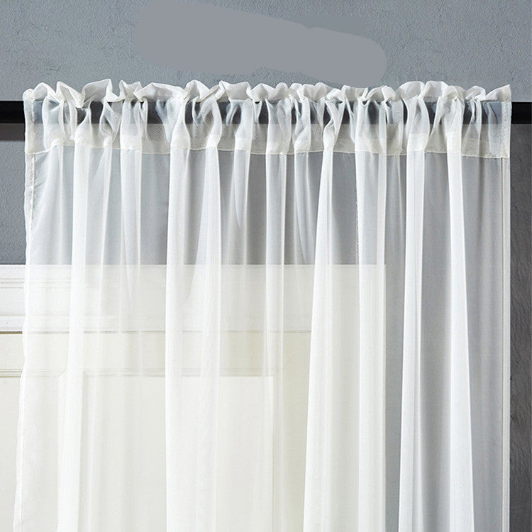 A pair of white, solid color cotton and linen window curtains hanging on a rod, with a door and a decorative item in the background.