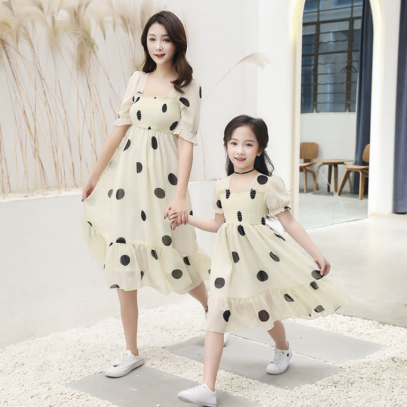 Two women in matching polka dot dresses standing indoors.
