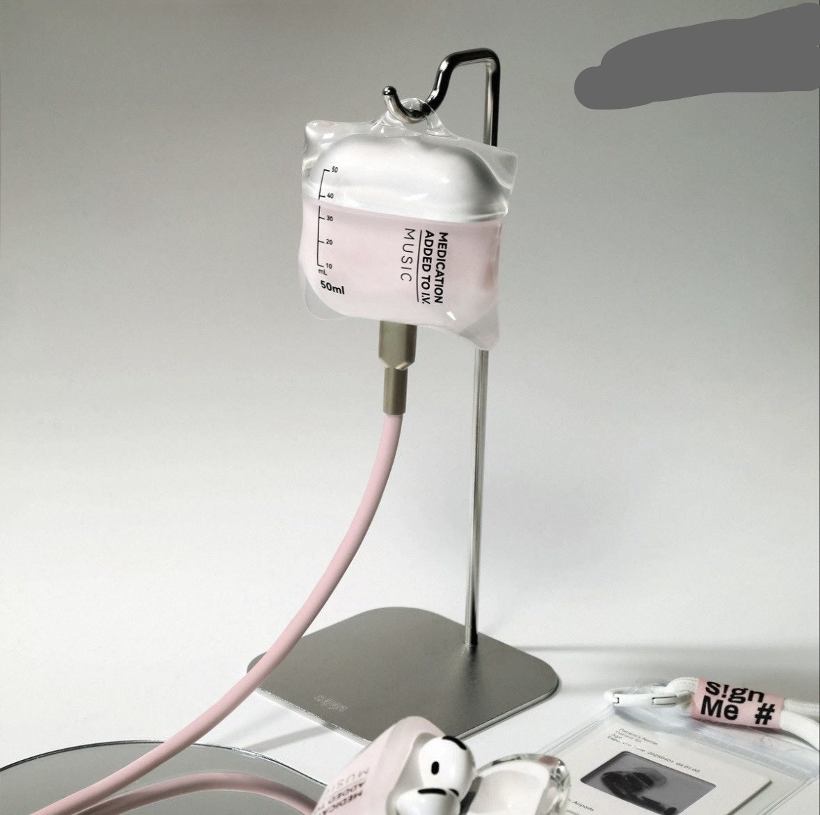 Intravenous drip-shaped earphone case with pink cable on a gray background