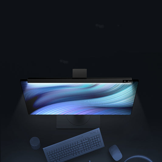 Modern desk setup with a large monitor, keyboard, and mouse in a dark room.