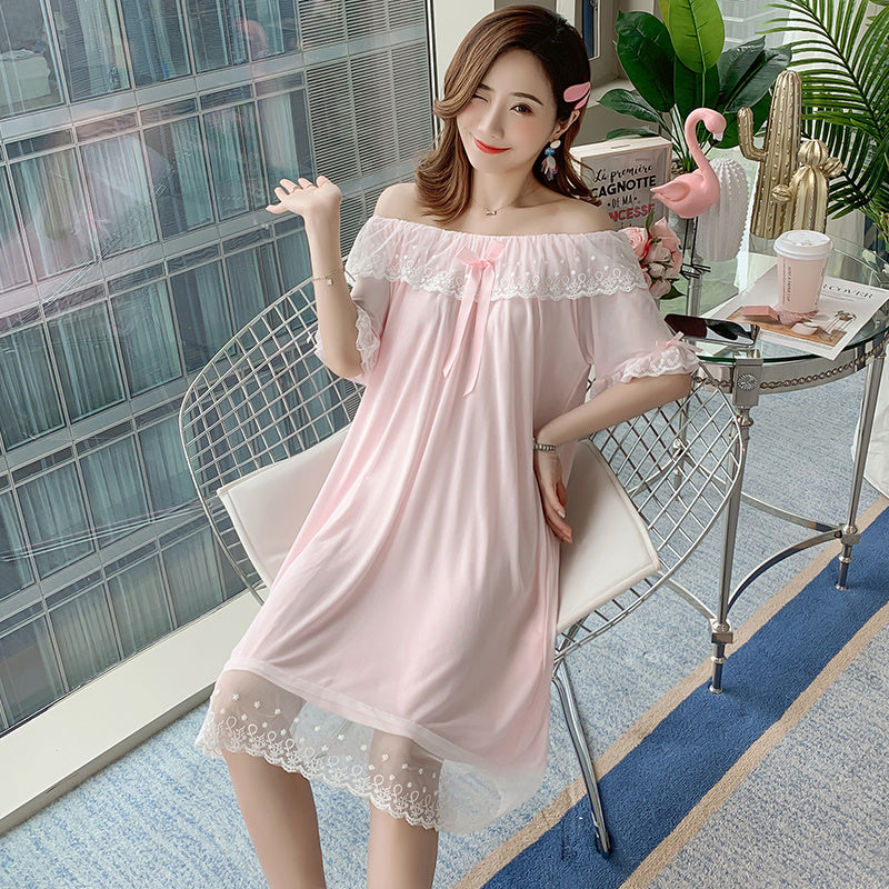 A woman sitting on a bathroom counter wearing a black nightgown with a square neckline and lace details.