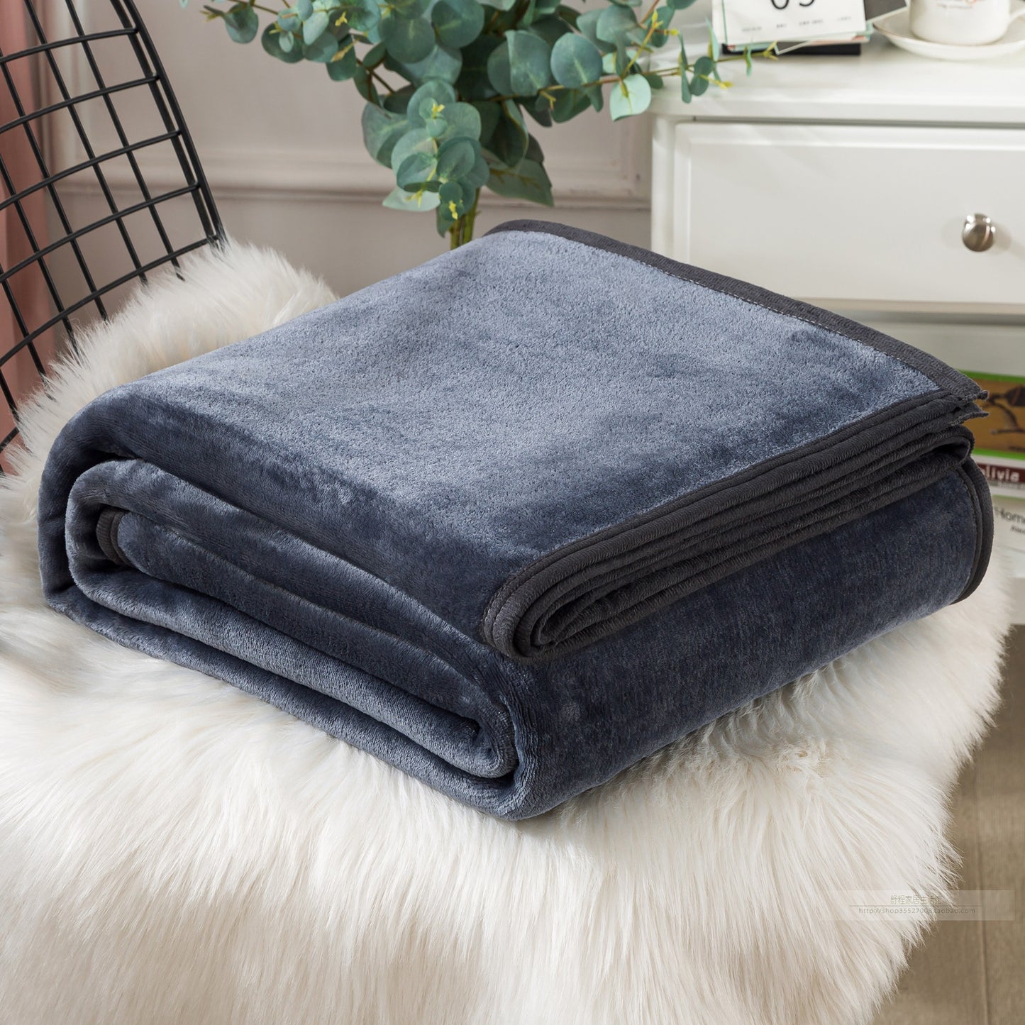 Folded dark blue blanket on a fluffy white surface.