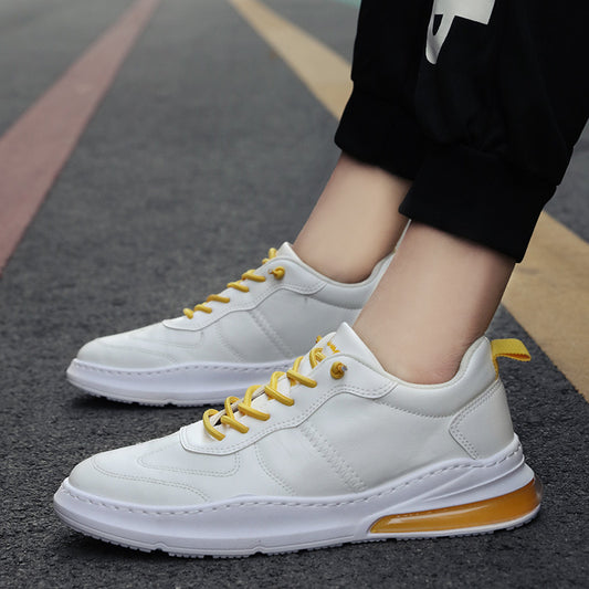 White sneakers with yellow laces and sole on a blurred street background