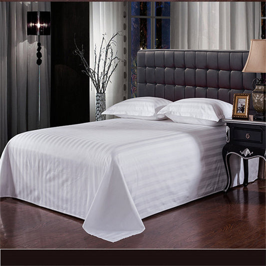 Bed with white sheets and a gray headboard in a dimly lit room.