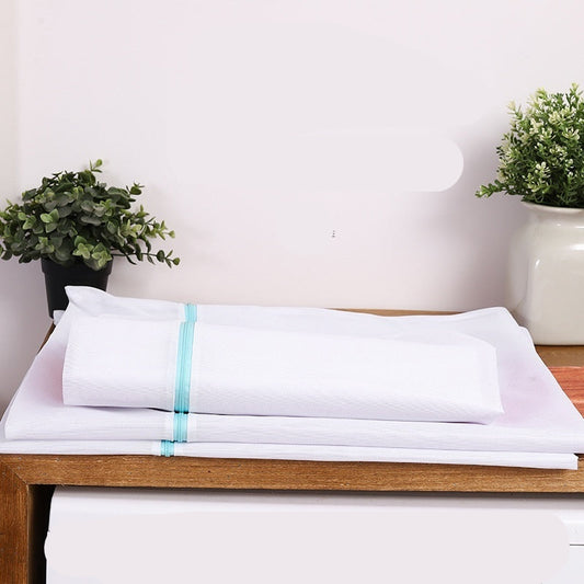 White laundry bag with a blue tag on a wooden surface in front of a Galanz washing machine, with plants in the background.