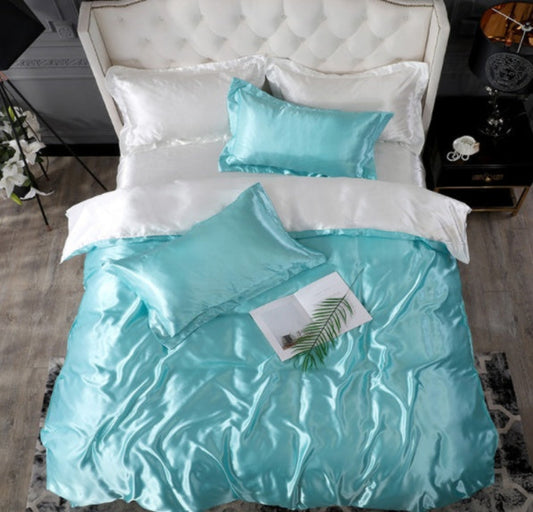 A set of bedding with a quilt cover and pillowcases in a solid water blue color, displayed on a bed with a white background.