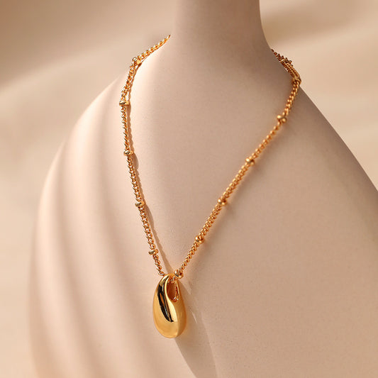 Gold necklace with a pendant on a mannequin against a beige background