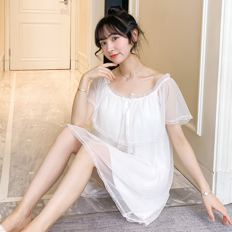 Woman wearing a white nightgown sitting on a bed in a bedroom.