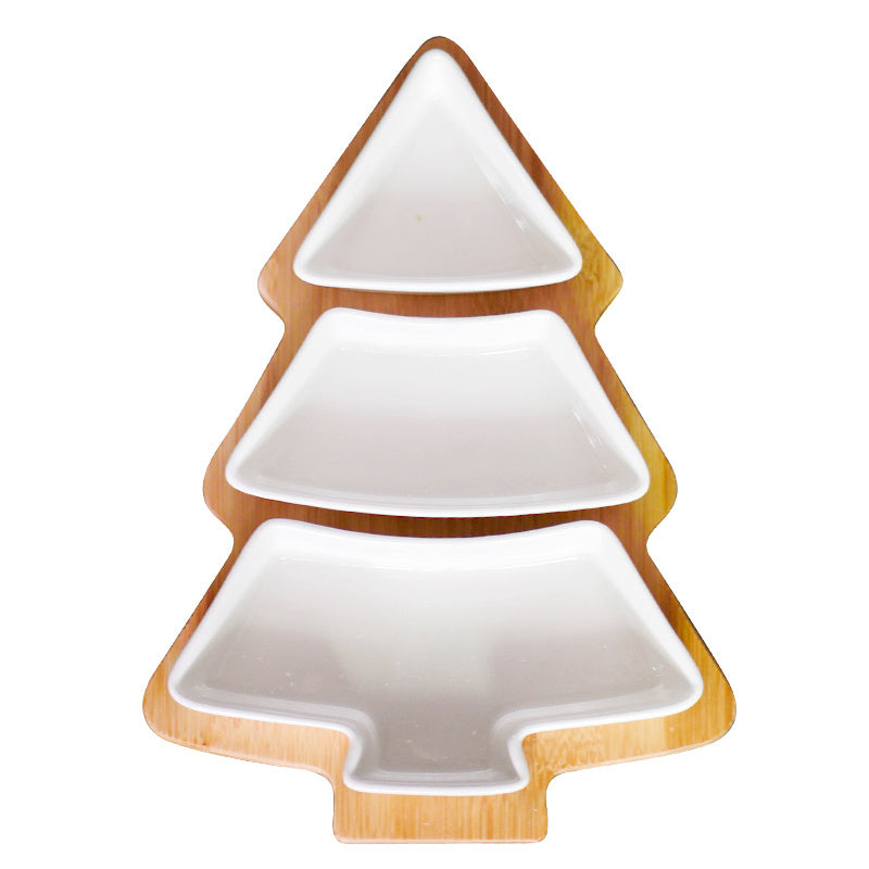 A set of Christmas tree-shaped ceramic plates in white, with the top plate holding gold-colored items, the middle plate with red items, and the bottom plate with green items, presented on a green background with holiday decorations.