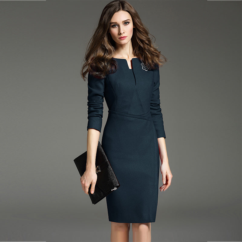 A woman in a professional setting wearing a mid-sleeve, solid color, midi-length dress in a dark color, holding a clutch bag.