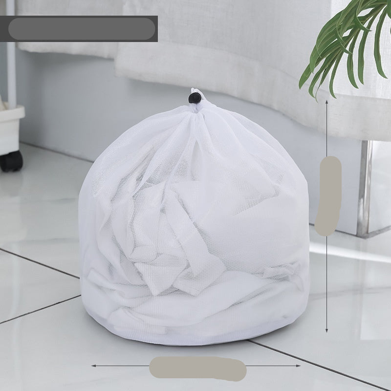 Two white mesh laundry bags filled with laundry standing in front of a washing machine with a person partially visible in the background.