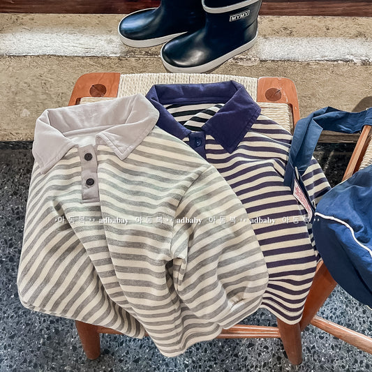 Children's striped shirts on a chair with a child wearing navy rain boots in the background.