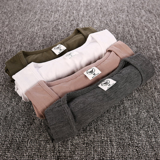 Four pairs of underwear in different colors stacked on a textured surface