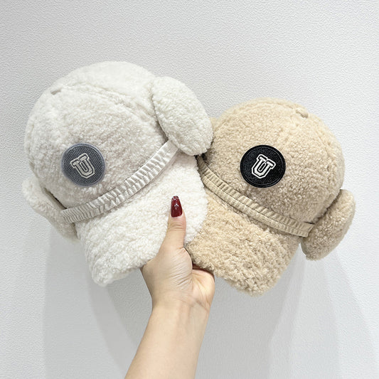 Two plush slippers with ear flaps held by a hand against a white background