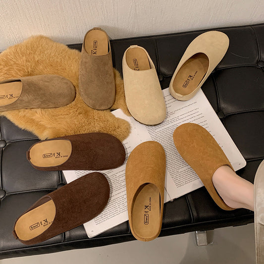 Various pairs of slippers on a black leather bench with a newspaper underneath.