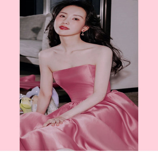 Woman in a pink dress sitting on a couch with a blurred background