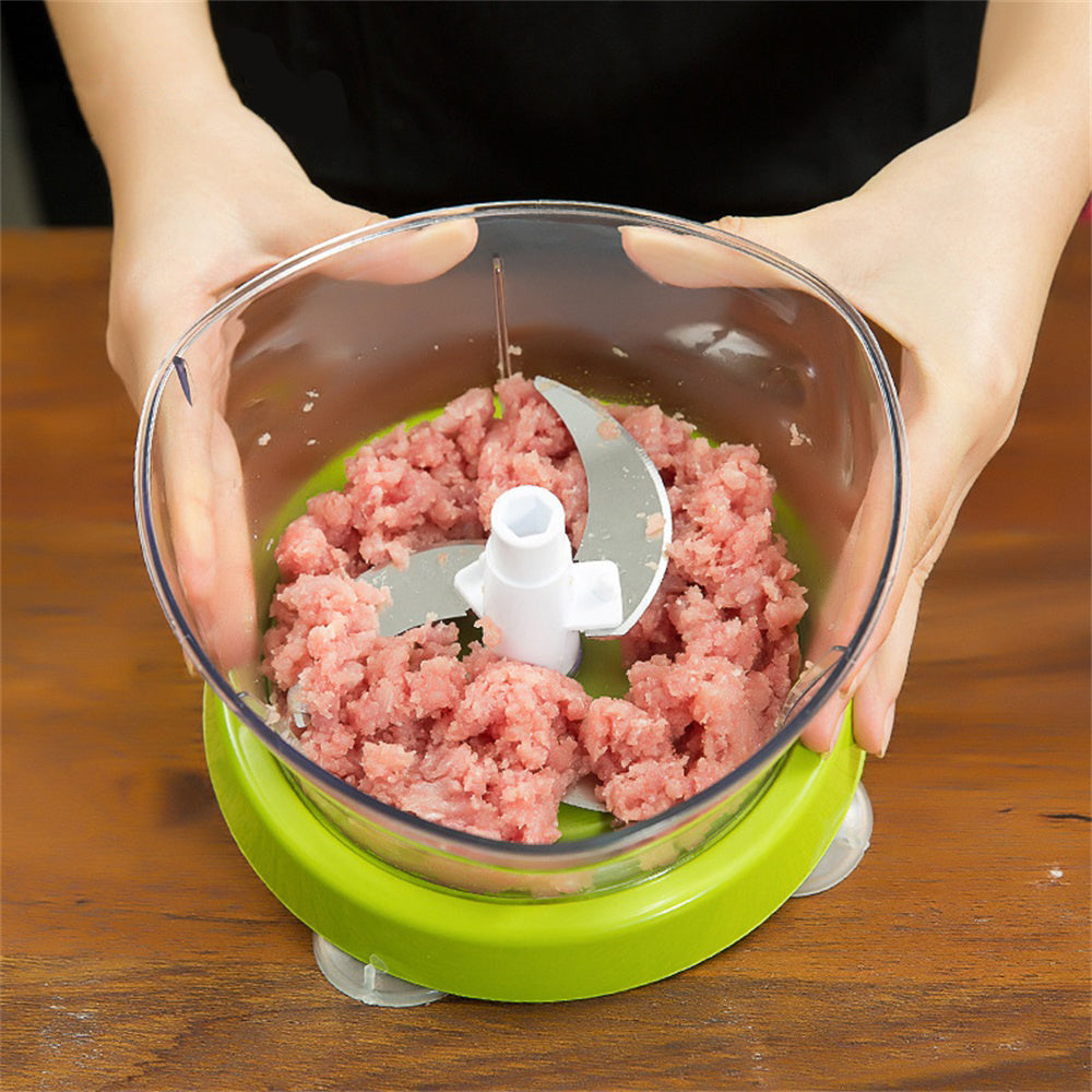Handheld food grinder with ground meat on a wooden surface
