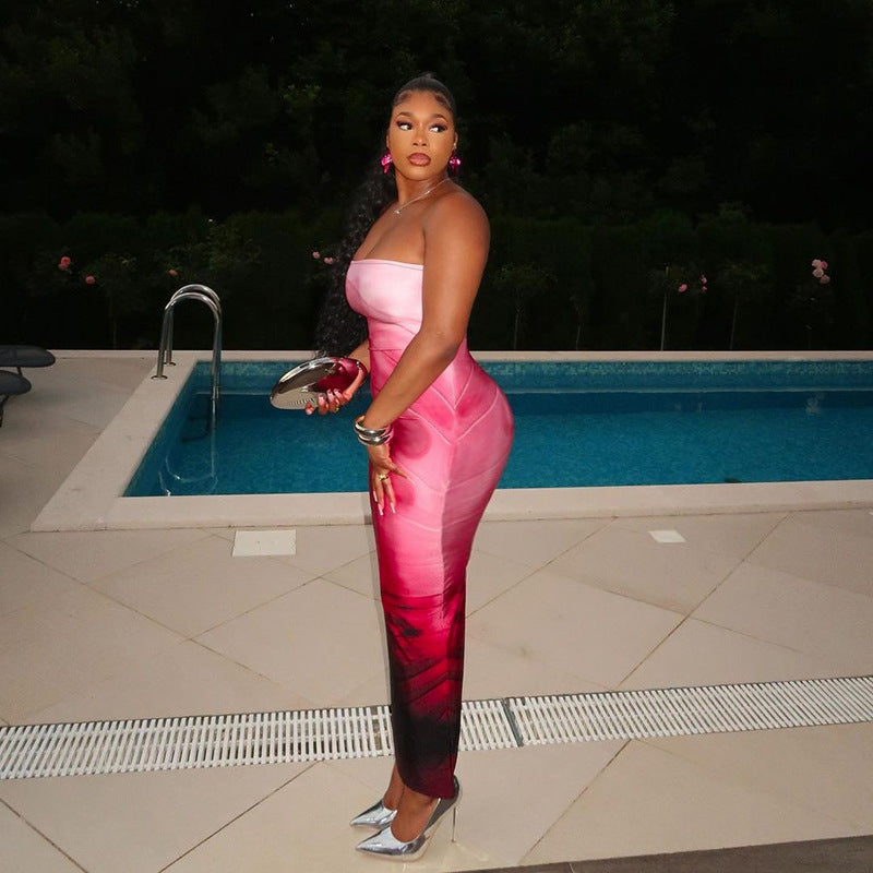 Woman in a pink and black dress standing by a pool at night.