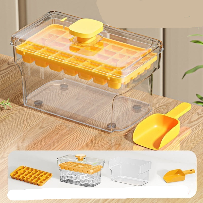Yellow ice cube tray with clear lid and scoop on a wooden surface