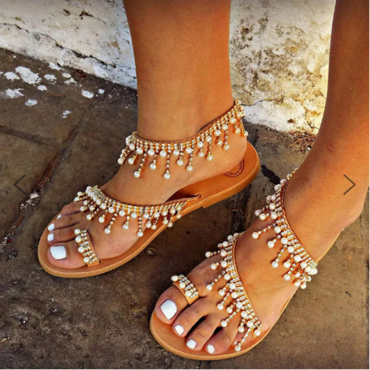 Beaded sandals on feet with a textured ground background