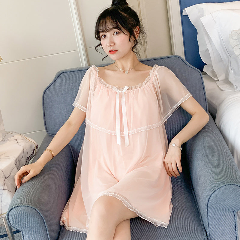 A woman sitting on a bathroom counter wearing a black nightgown with a square neckline and lace details.