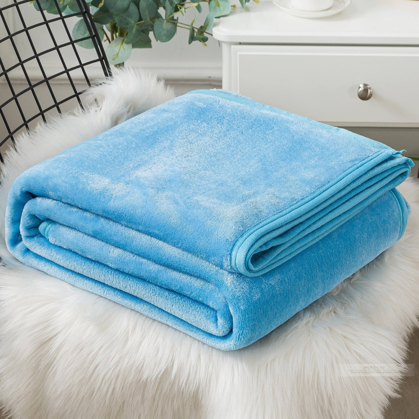 Blue plush blanket on a white fur surface.