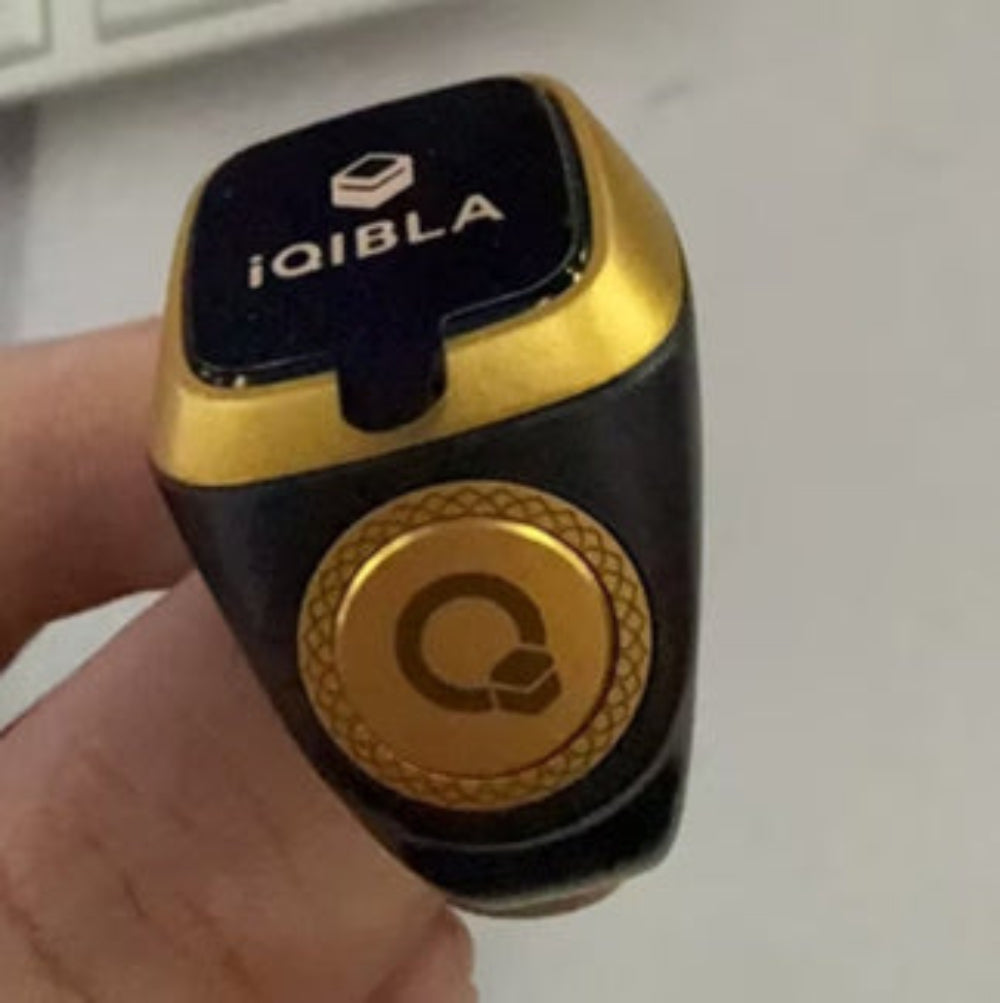Black and gold device with 'iQIBLA' branding held by a hand.