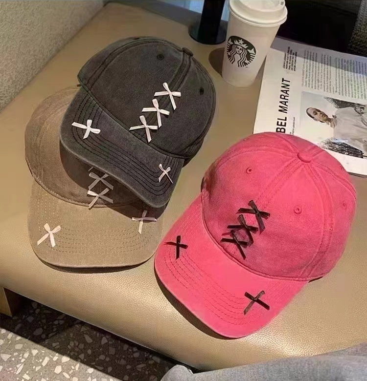 Three caps with unique designs on a surface, including a Starbucks cup and newspaper.