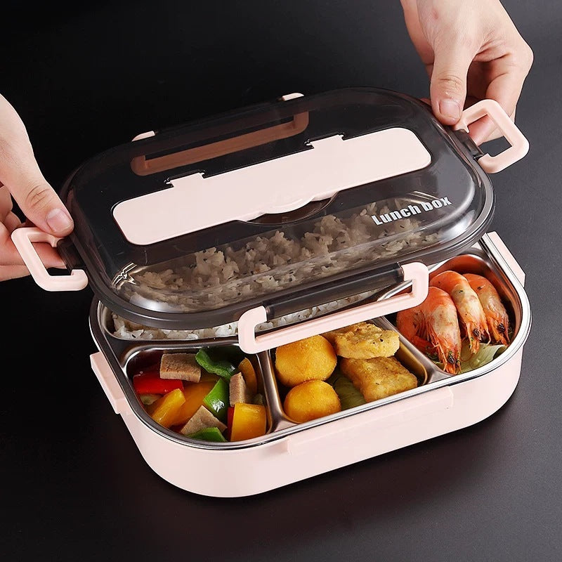 Top view of a stainless steel insulated lunch box with compartments containing rice, fruits, and vegetables. The lunch box has a blue and pink color scheme with a handle and a set of cutlery to the side.