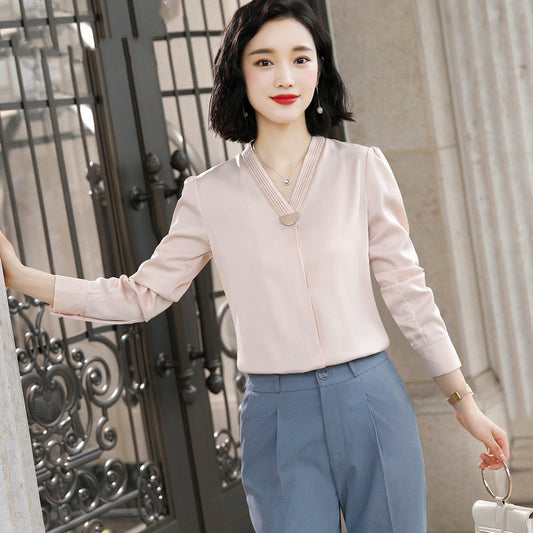 Woman wearing a light pink blouse and blue pants standing in front of an ornate gate.