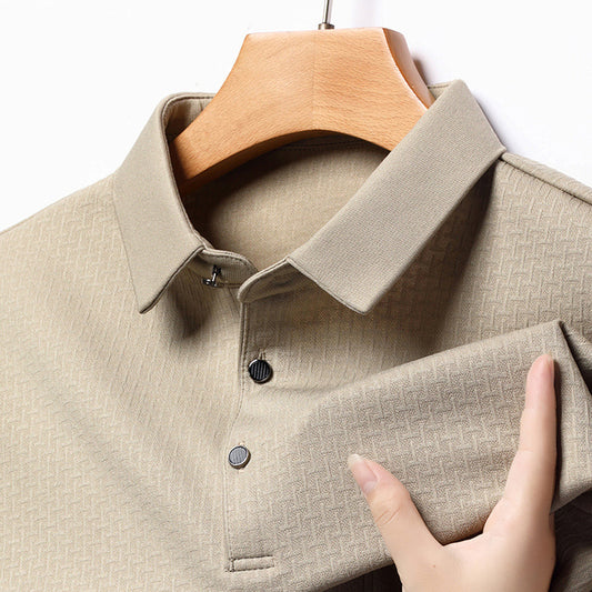 Beige shirt on a wooden hanger with a hand touching the fabric
