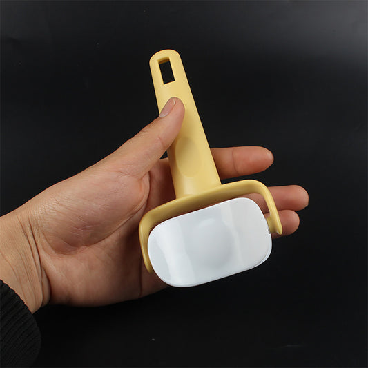 Hand holding a yellow and white cleaning tool against a black background