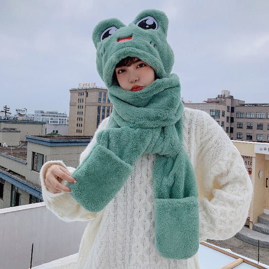 A child wearing a green frog-shaped hat, scarf, and gloves set