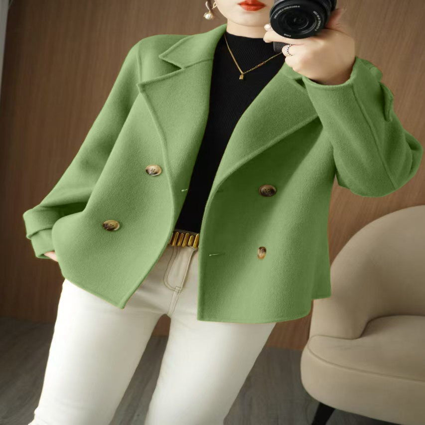 A person wearing a beige knee-length coat with long sleeves and double-breasted button details.