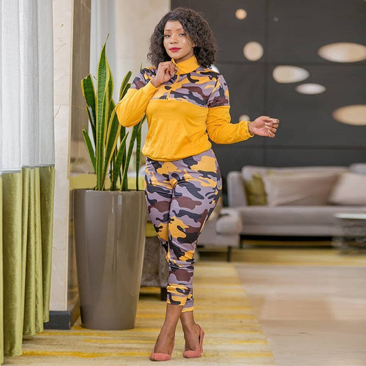 Woman in a yellow and camouflage outfit standing in a modern living room.