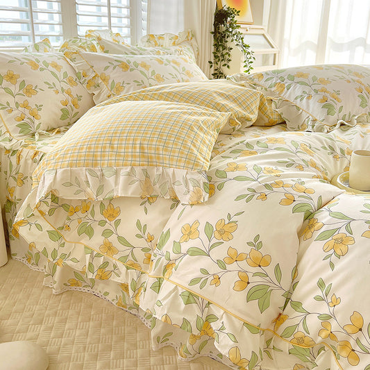 A four-piece bedding set with a floral pattern, including a bed skirt, quilt cover, and two pillowcases in matching design, displayed on a bed.