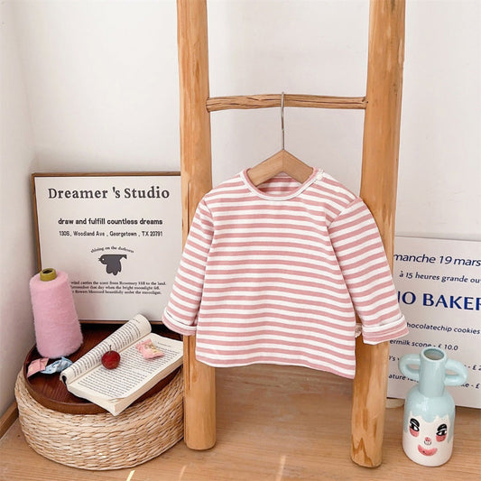 Pink and white striped shirt hanging on a wooden ladder with decorative items below.