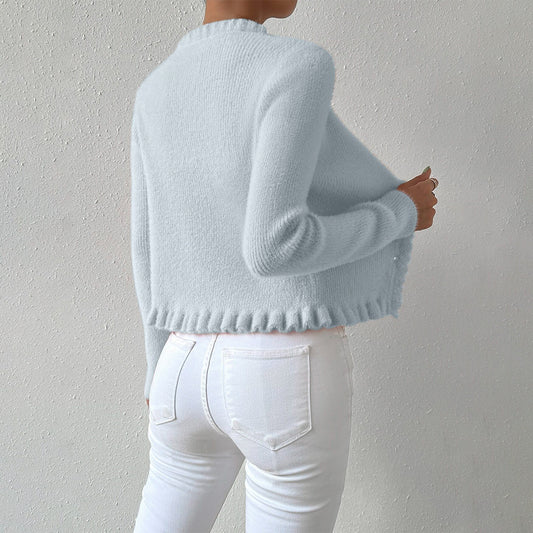 Person wearing a light blue sweater and white jeans against a plain background.