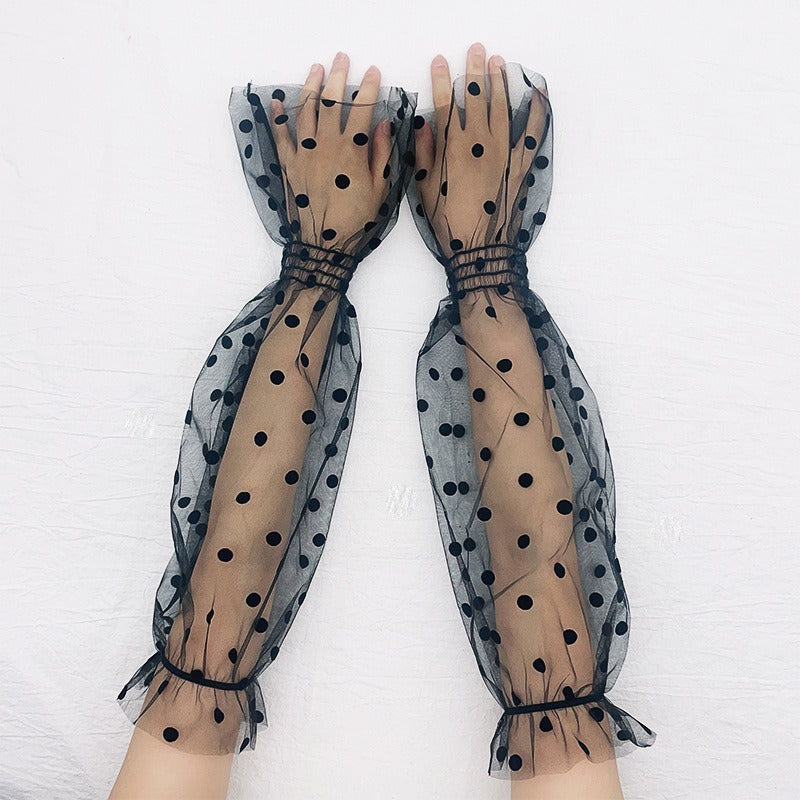 A pair of black mesh gloves with a polka dot pattern, featuring a love heart design on the sleeve.