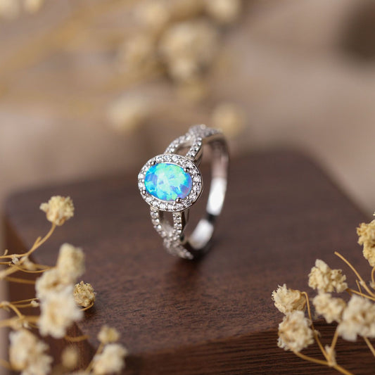 Silver ring with a blue gemstone on a wooden surface with dried flowers