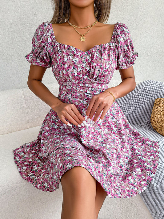 Woman wearing a floral dress sitting on a couch.